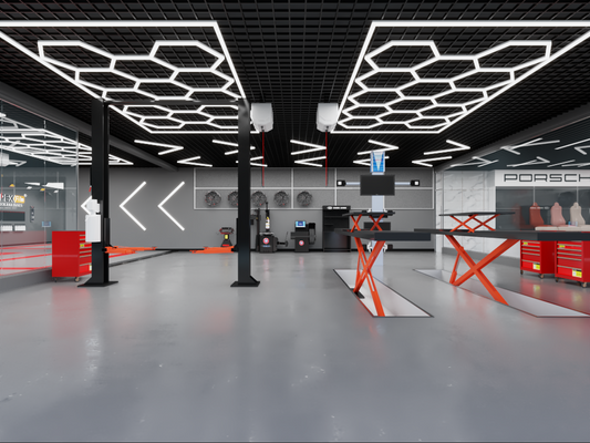 Moderne Werkstatt mit Hexagon-LED-Beleuchtungssystem an der Decke, das helles, gleichmäßiges Licht in 6500K bietet. Die Werkstatt ist ausgestattet mit Hebebühnen, roten Werkbänken und High-End-Equipment, ideal für Autodetailing oder Reparaturen. Porsche-Werkstattbereich im Hintergrund